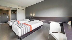 Hotellihuone, jossa on kaksi sänkyä, työpöytä, tuoli ja vaatekaappi.