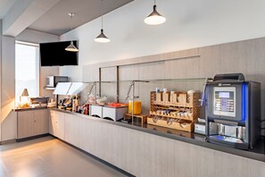 Moderni keittiö, jossa on kahvinkeitin, lasinen työtaso ja puiset kaapit.