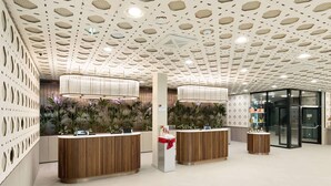 Un área de recepción con mostradores de madera, techo con diseño y entrada de vidrio.