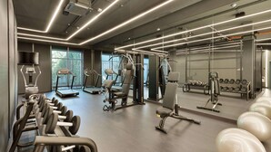 Un gimnasio moderno con diversos equipos de ejercicio, ventanas amplias y un diseño limpio y espacioso.