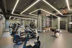 Un gimnasio moderno con cintas de correr, elípticas y un banco.
