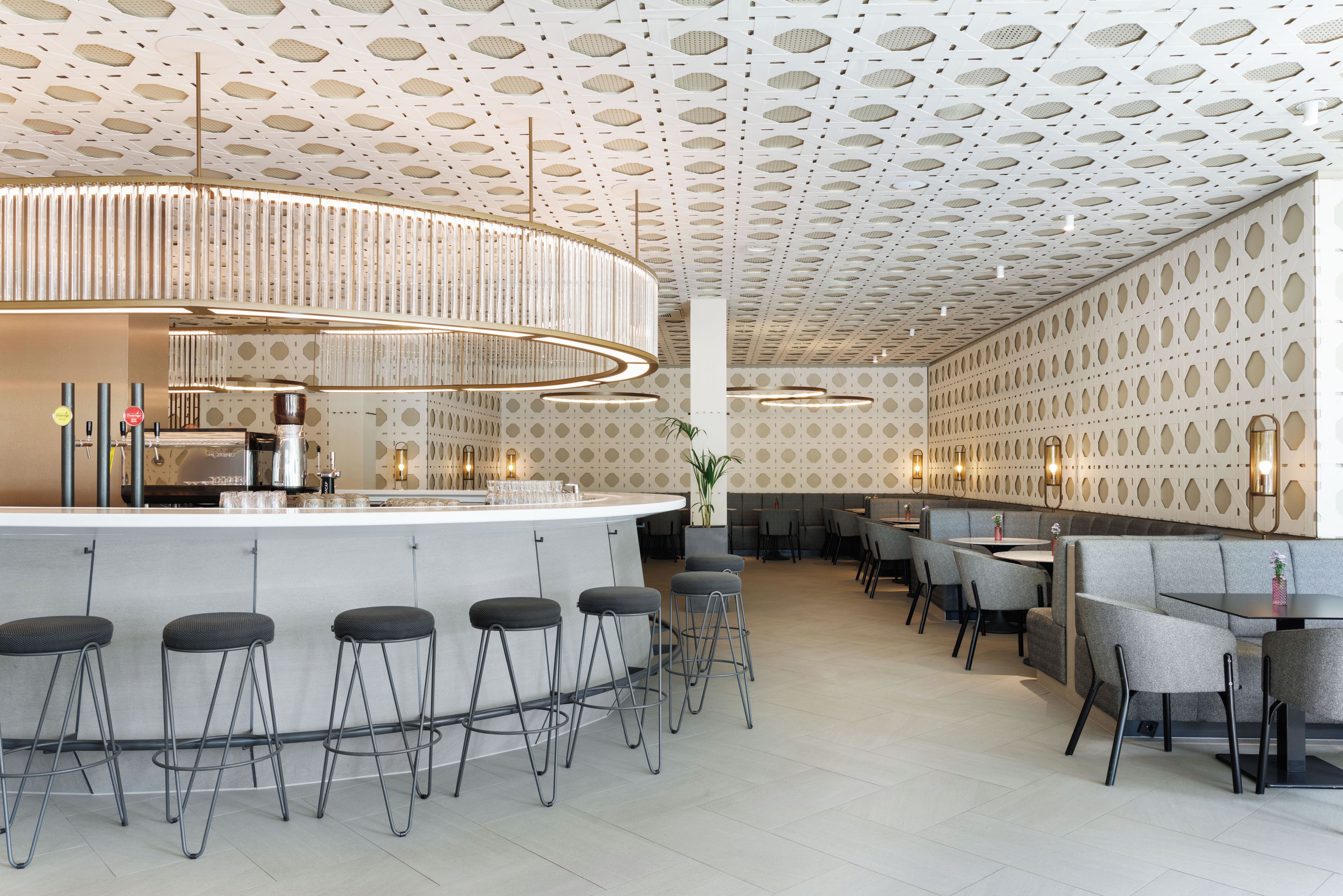 Uma área de bar moderna com design de teto diferenciado, banquetas e assentos.