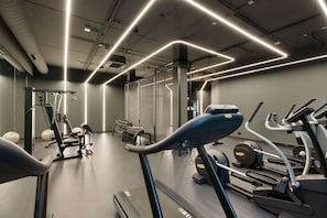 Un gimnasio moderno con cintas de correr, máquinas de pesas y pelotas de ejercicio.