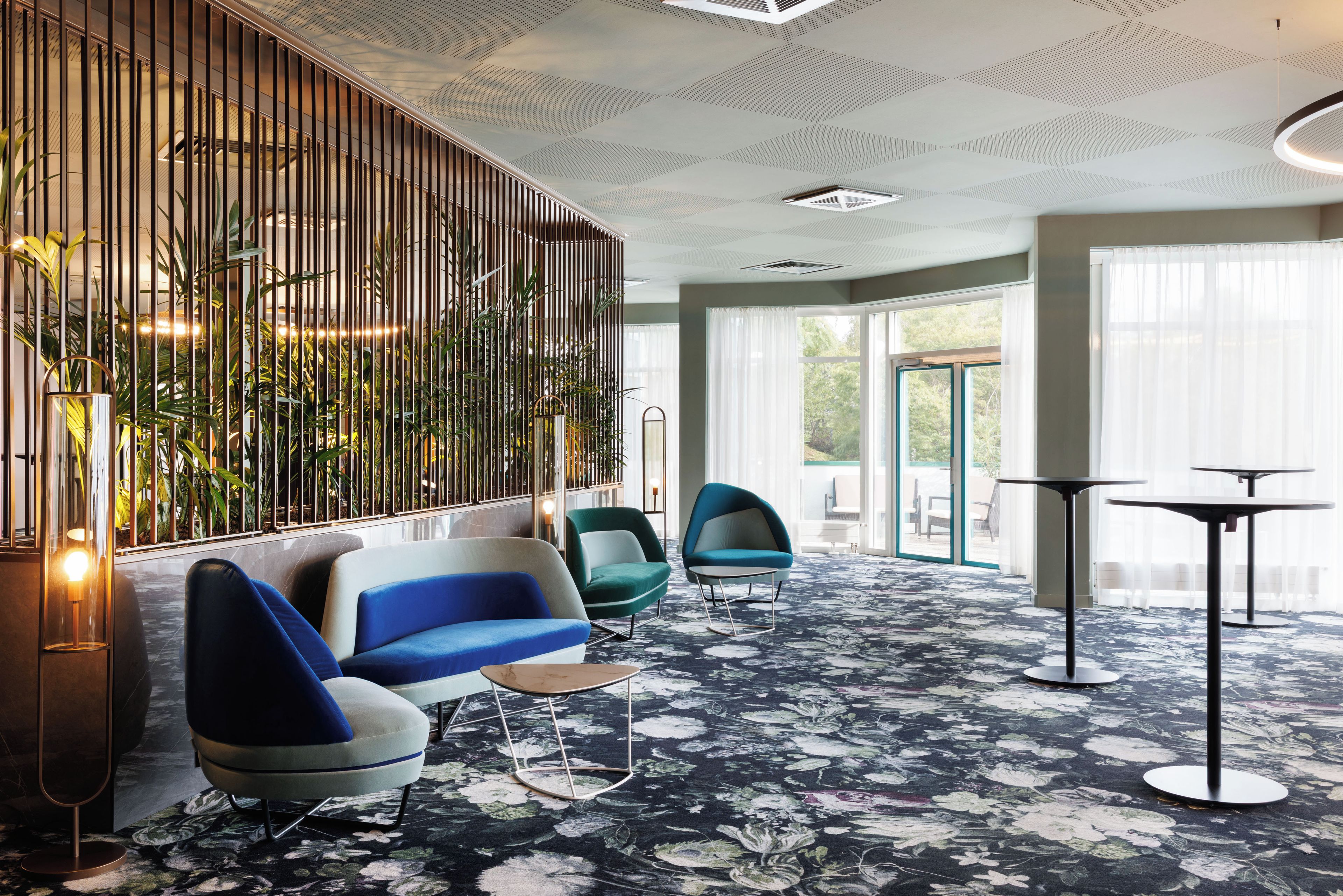 A modern lobby with a seating area, a decorative wall, and a large window.