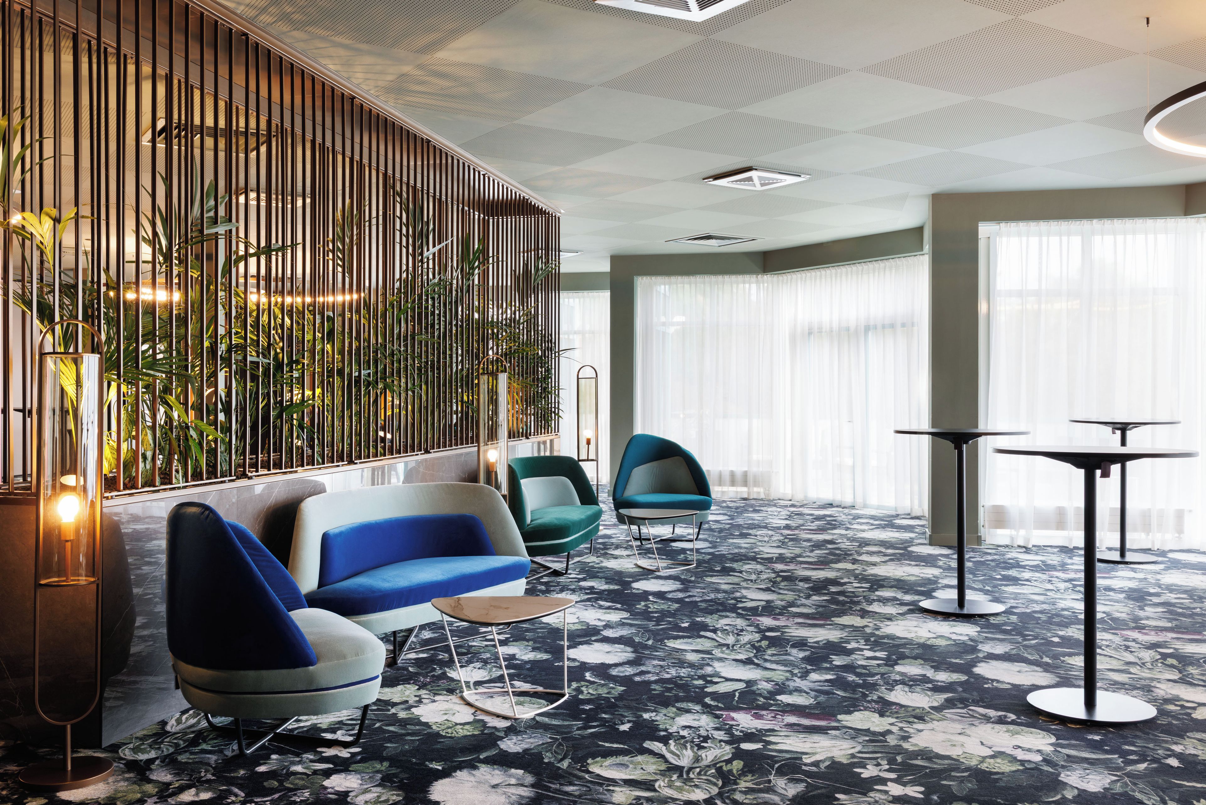 A modern hotel lobby with a seating area, a decorative plant wall, and a patterned carpet.