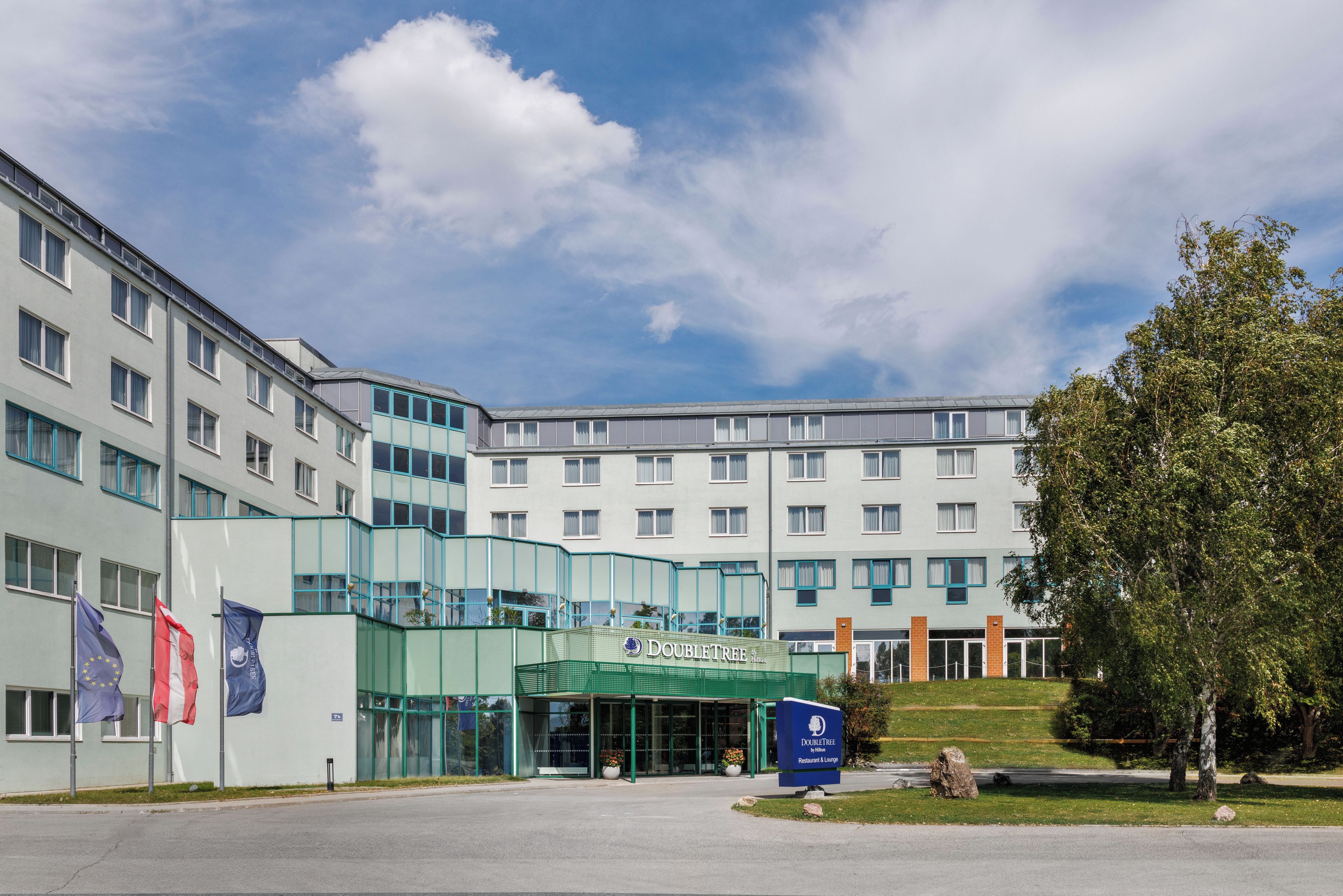 A hotel with a modern facade, multiple windows, and a prominent entrance with a sign.
