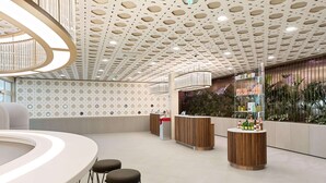Una moderna zona de recepción con un mostrador circular, taburetes de bar y un techo decorativo.