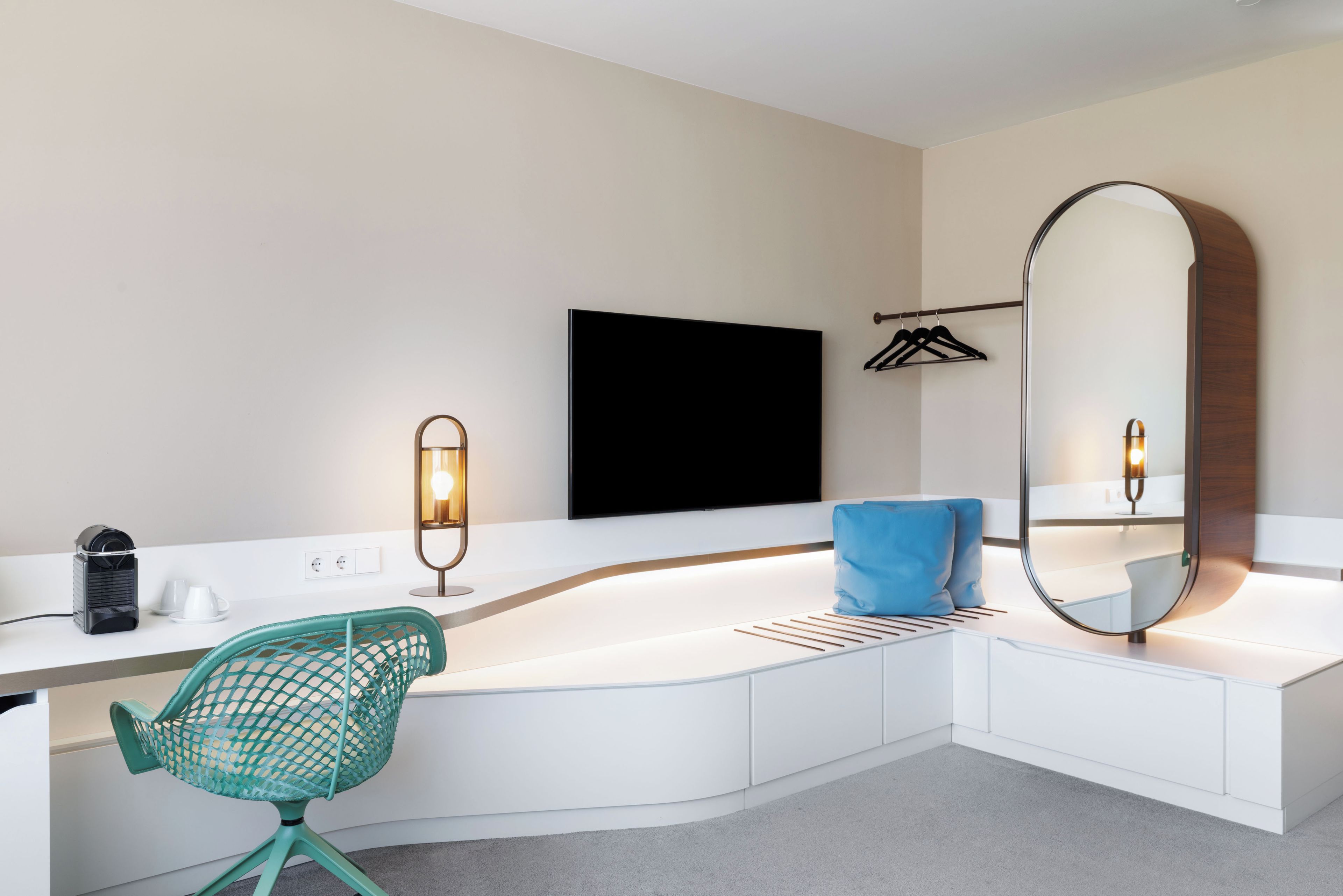 A modern bathroom with a white vanity, a large mirror, a sink, and a green chair.