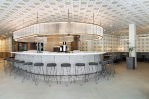 Zona de bar moderna con barra circular, varios taburetes y un diseño de techo original.