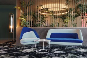 A modern lounge area with a blue and white sofa, a matching armchair, and a small round table. - DoubleTree by Hilton Vienna Bosei (Vienna)