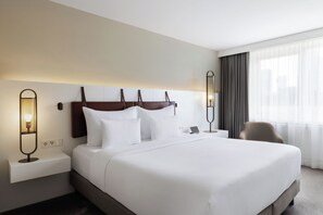 A hotel room with a large bed, bedside tables, a chair, and a window with curtains. - DoubleTree by Hilton Vienna Bosei (Vienna)