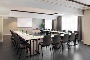 Un salón de conferencias con una larga mesa, sillas y botellas de agua.