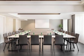 A conference room with a long table, multiple chairs, and a plant. - DoubleTree by Hilton Vienna Bosei (Vienna)