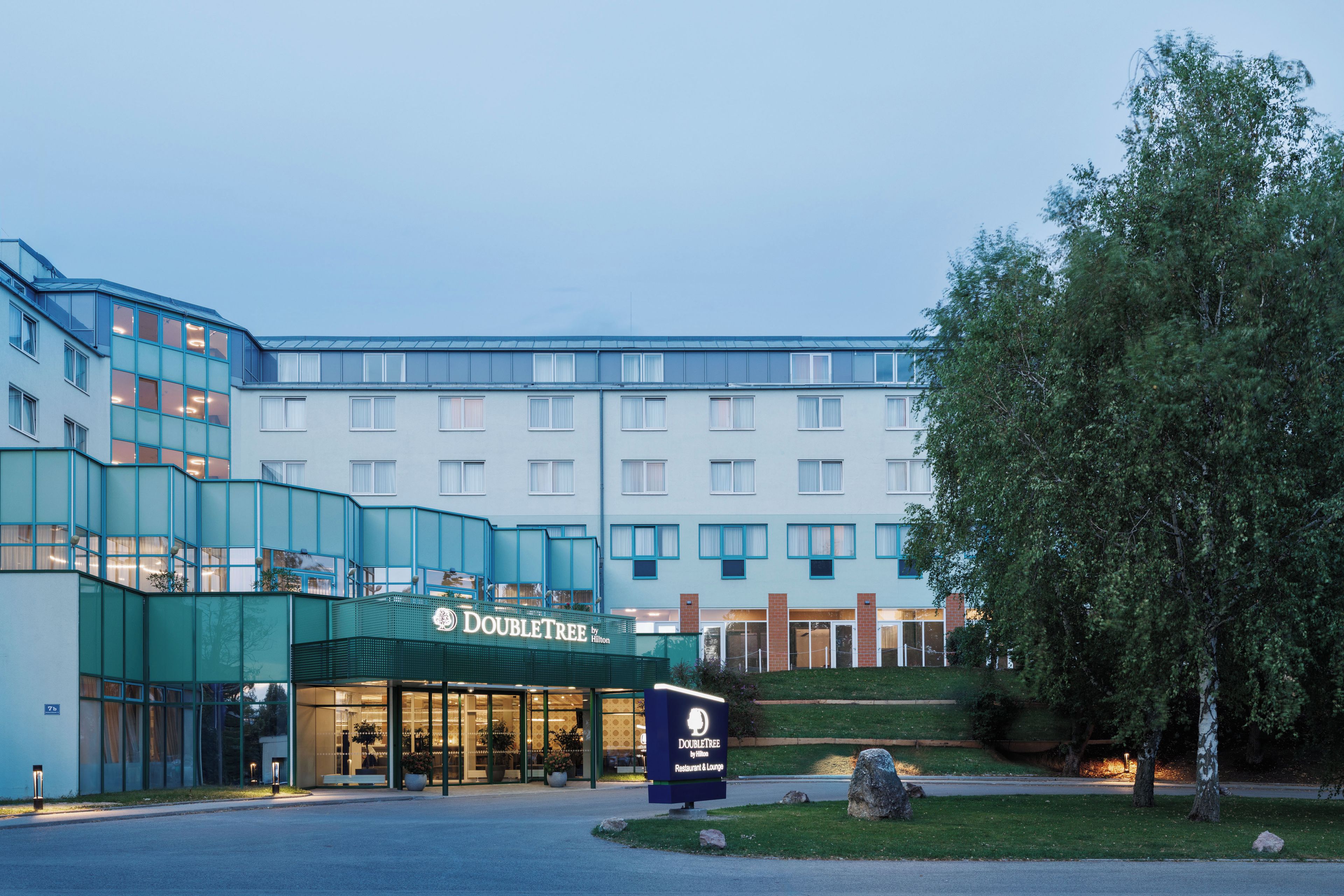 A hotel with a modern design, featuring a prominent entrance with glass doors and a sign for the DoubleTree by Hilton.