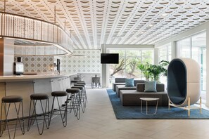 Zona de bar moderna con taburetes, una barra y una pantalla de televisión.