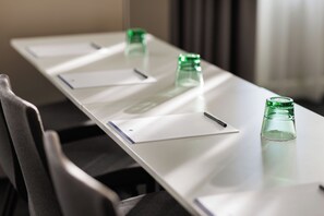 A conference table with documents, pens, and green glass bottles. - DoubleTree by Hilton Vienna Bosei (Vienna)