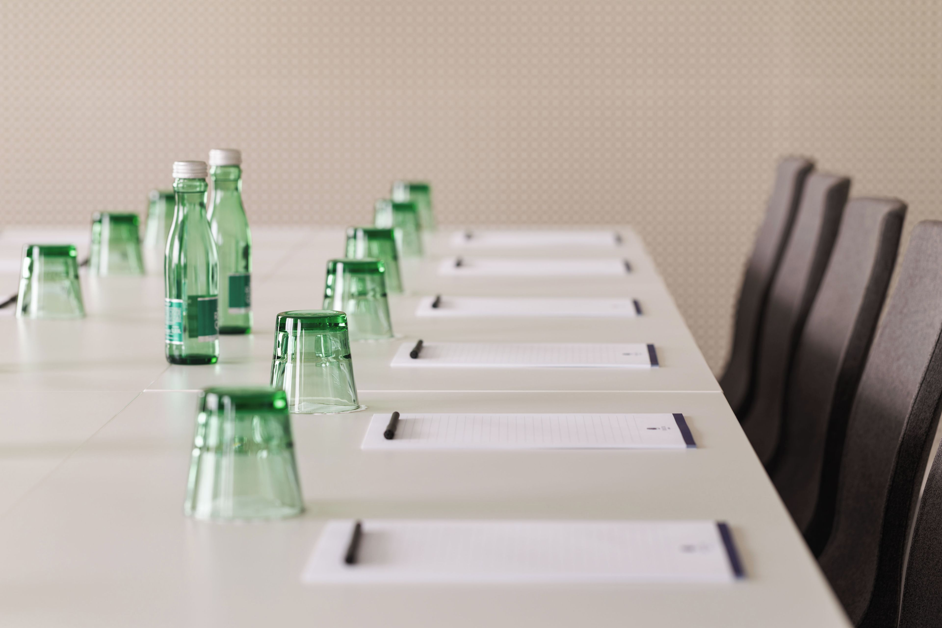 A conference table with green glass bottles and name cards.