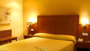 A hotel room with a large bed, two bedside tables, a wooden headboard, and two wall-mounted lamps. - Casa Quiquet (Beniparrell)
