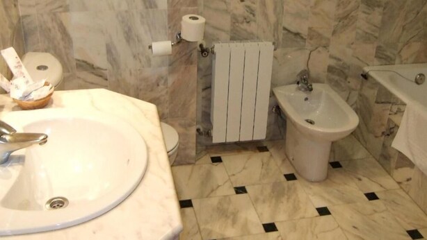 A bathroom with a sink, bidet, toilet, marble walls, and a tiled floor. - Casa Quiquet (Beniparrell)
