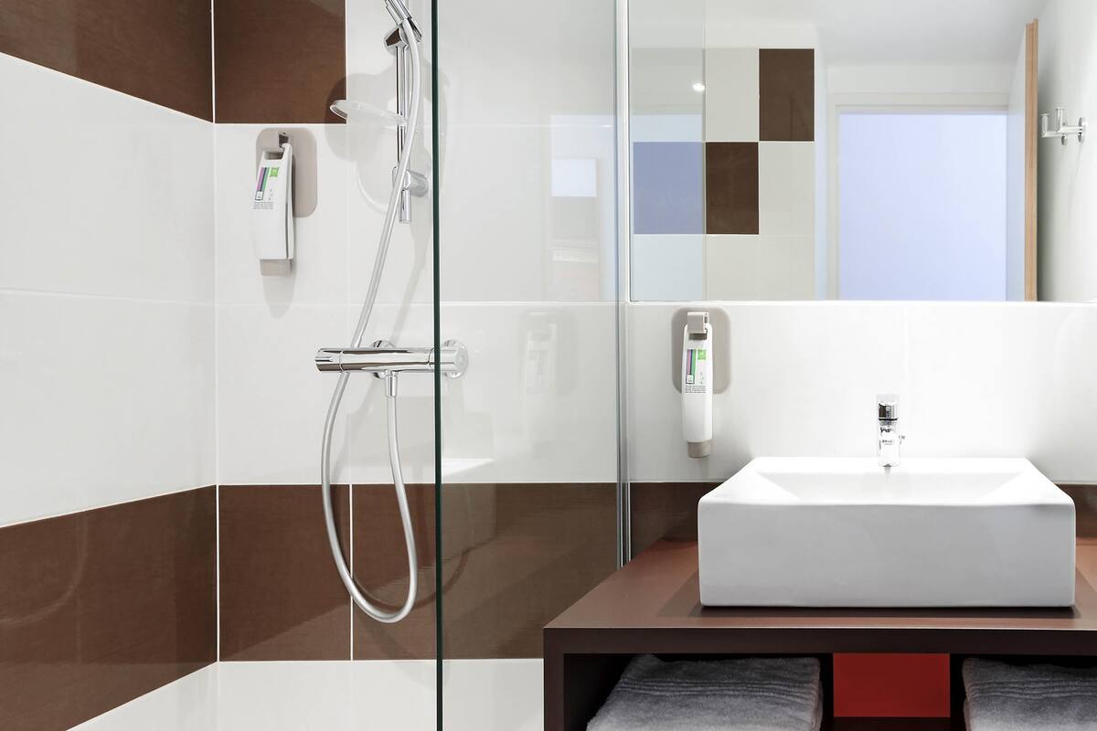 Ein modernes Badezimmer mit Duschkabine aus Glas, einem weißen Waschbecken und einem Handtuchhalter.