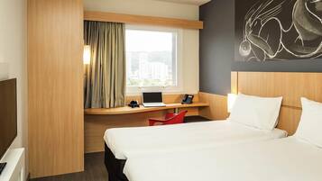 Une chambre d’hôtel comprenant un lit, un bureau avec un ordinateur portable, un téléphone et une chaise.