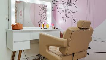 Un tocador con espejo, productos de maquillaje y una silla.