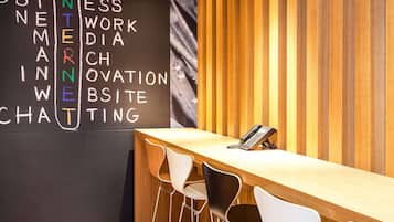 Un espacio de trabajo moderno con un escritorio de madera, dos sillas blancas y un teléfono montado en la pared.