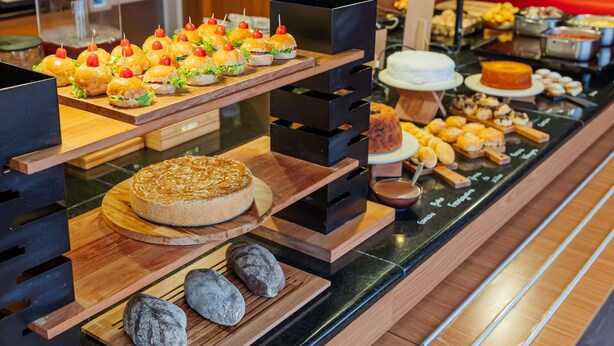 Un buffet proposant une variété de plats, notamment des sandwichs, des gâteaux et des pâtisseries.