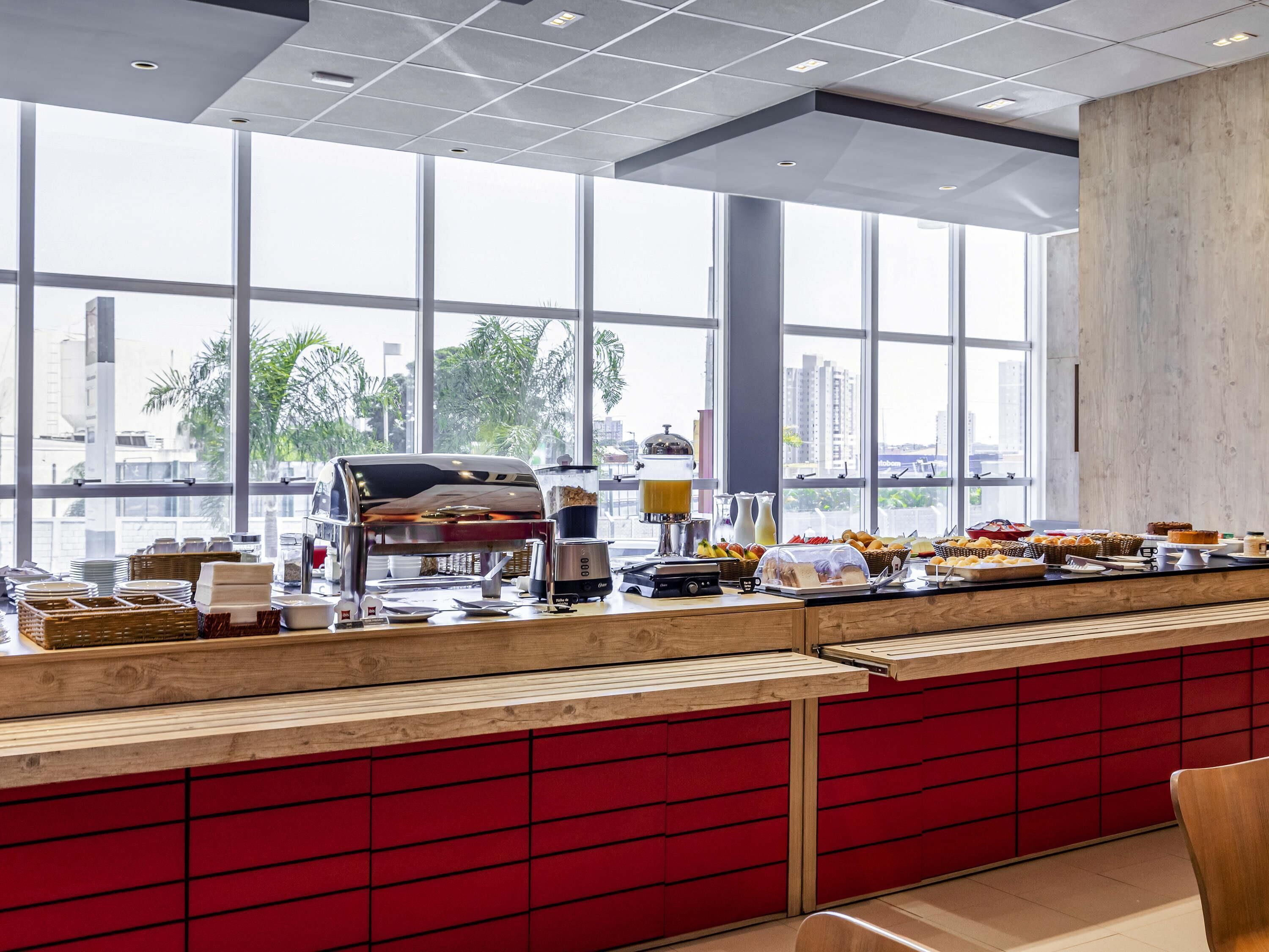 Un bufé de desayuno con una máquina de café, fruta y pasteles.