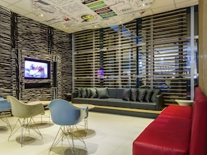 Un intérieur moderne comprenant un téléviseur, un coin salon et un mur orné de divers textes et inscriptions.