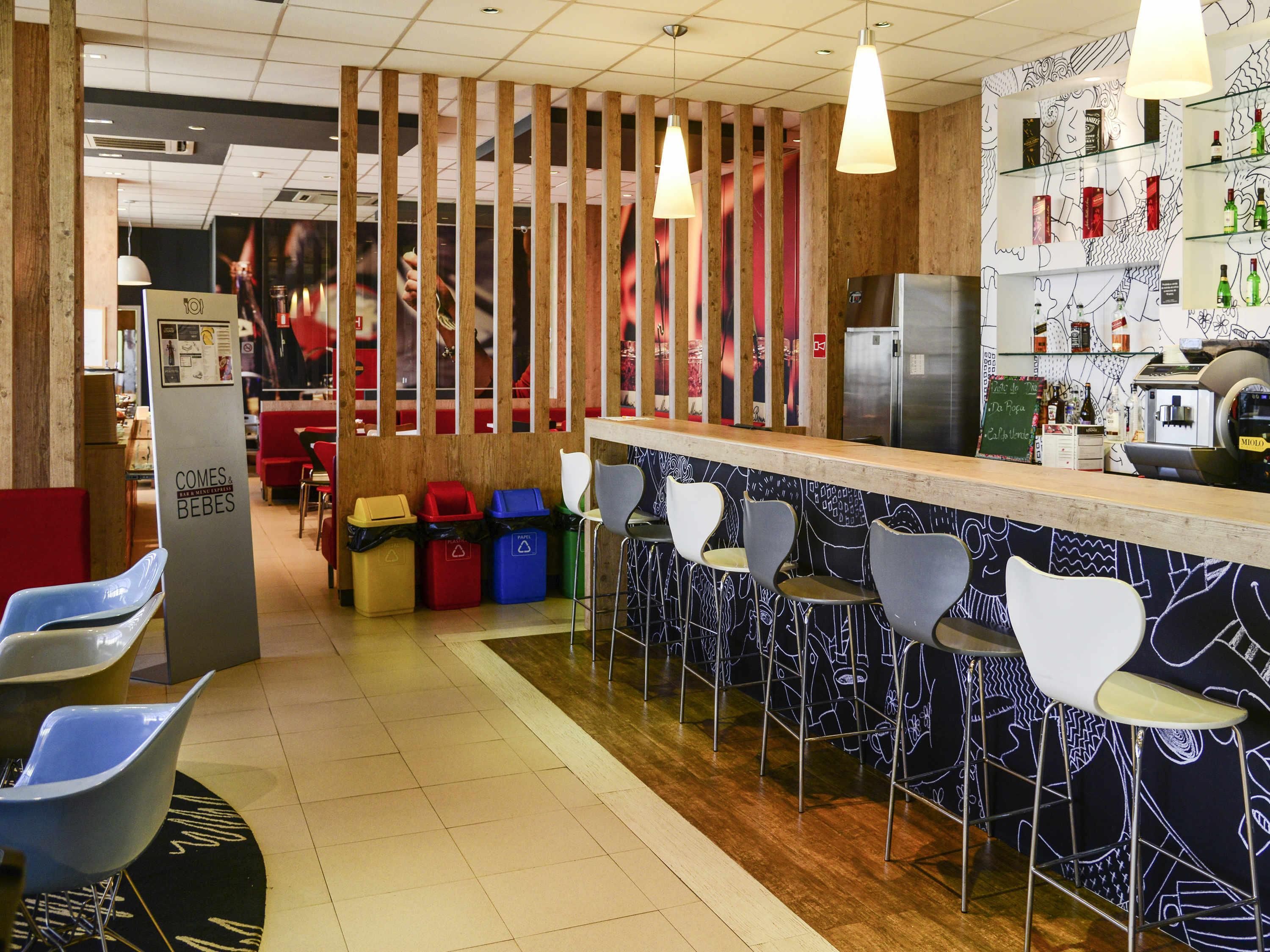 Un espace bar avec des tabourets, un comptoir et un réfrigérateur.