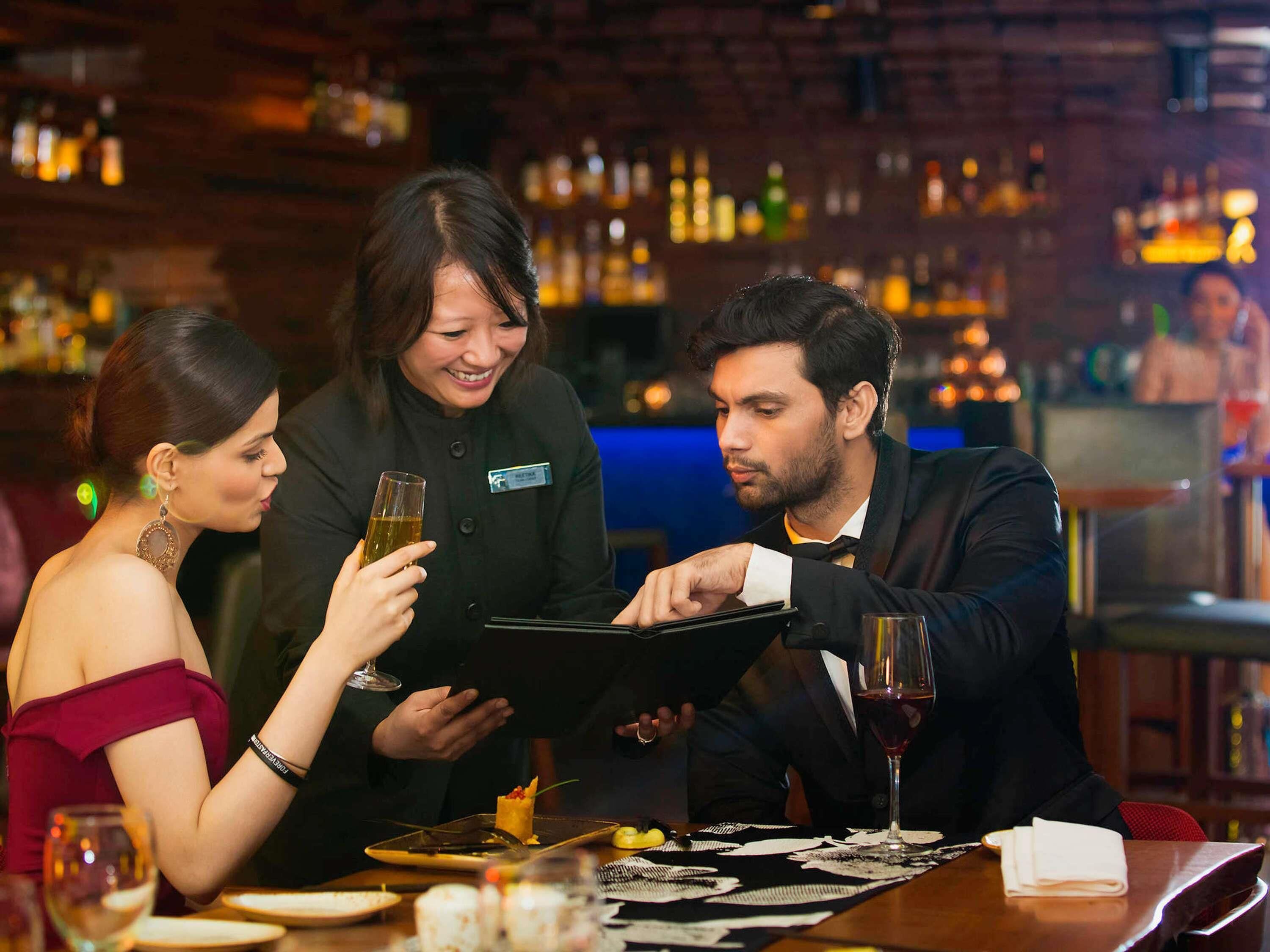 Un grupo de personas cenando en un restaurante con un bar al fondo.