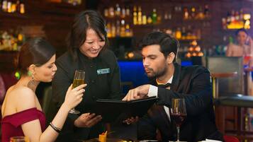 Un grupo de personas cenando en un restaurante con un bar al fondo.