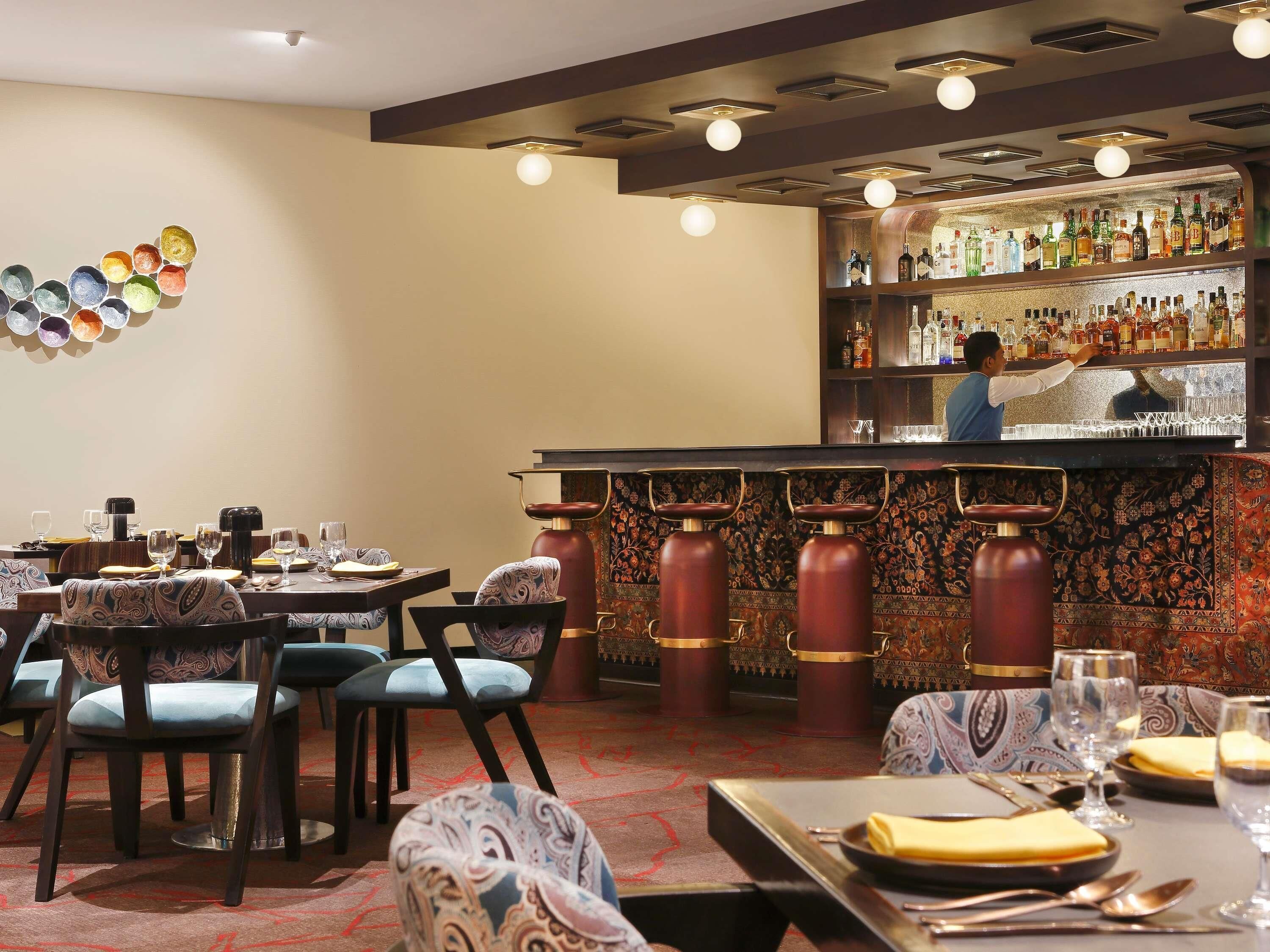 A restaurant interior with tables, chairs, a bar area, and a bartender.