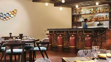 A restaurant interior with tables, chairs, a bar area, and a bartender.