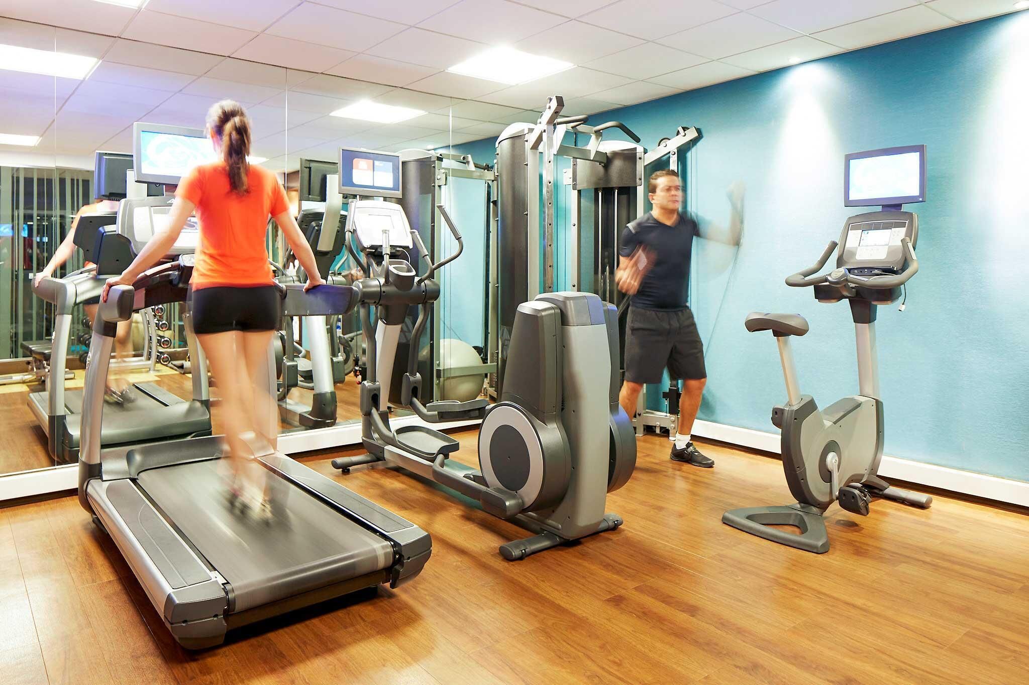 Une salle de sport équipée de tapis de course, de vélos elliptiques et d'appareils de musculation.