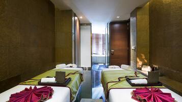 Two single beds with crisp linens and matching pillows, a large mirror, and a window offering a view of the outside.