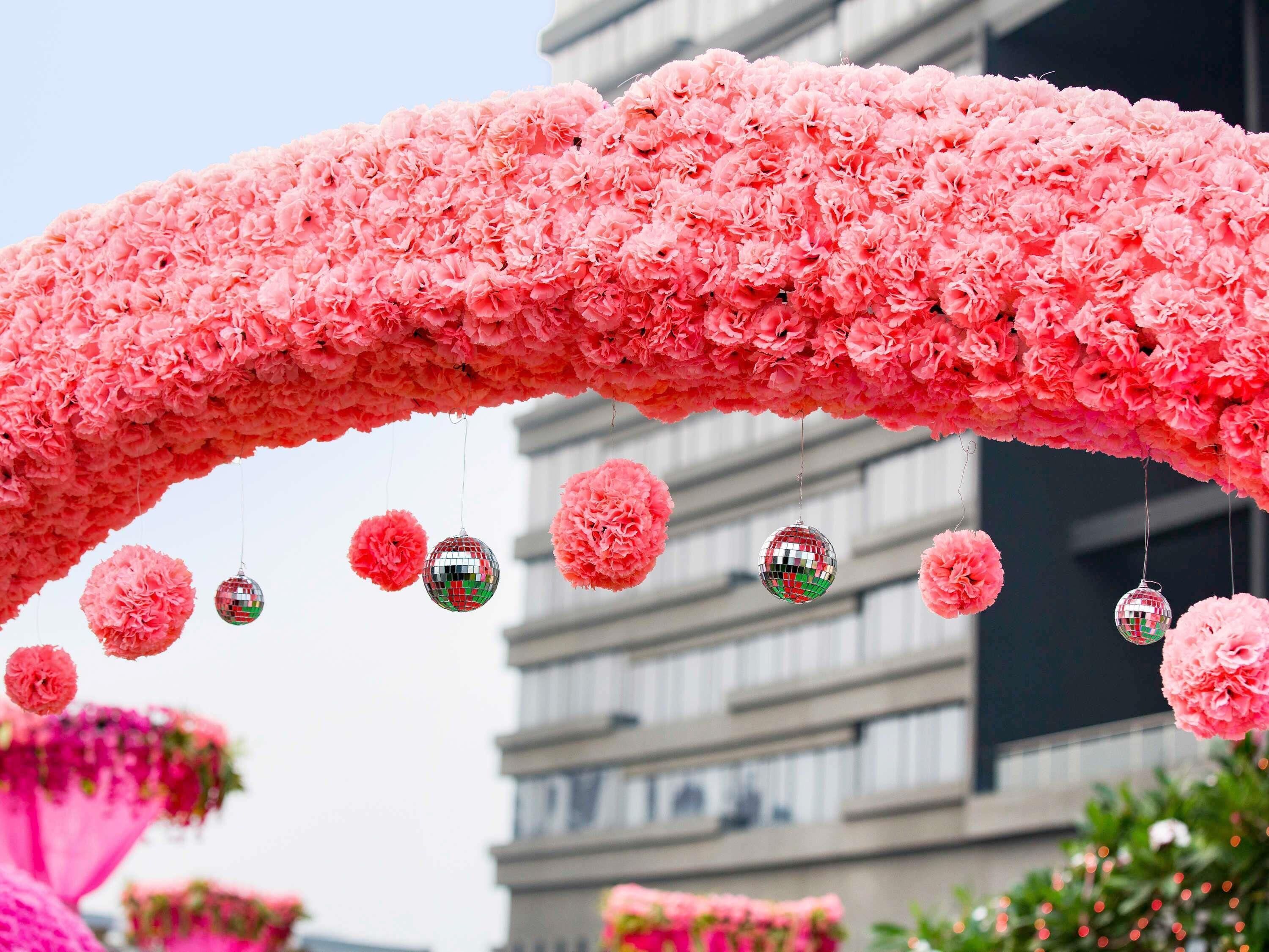 An arch of pink flowers with disco balls.