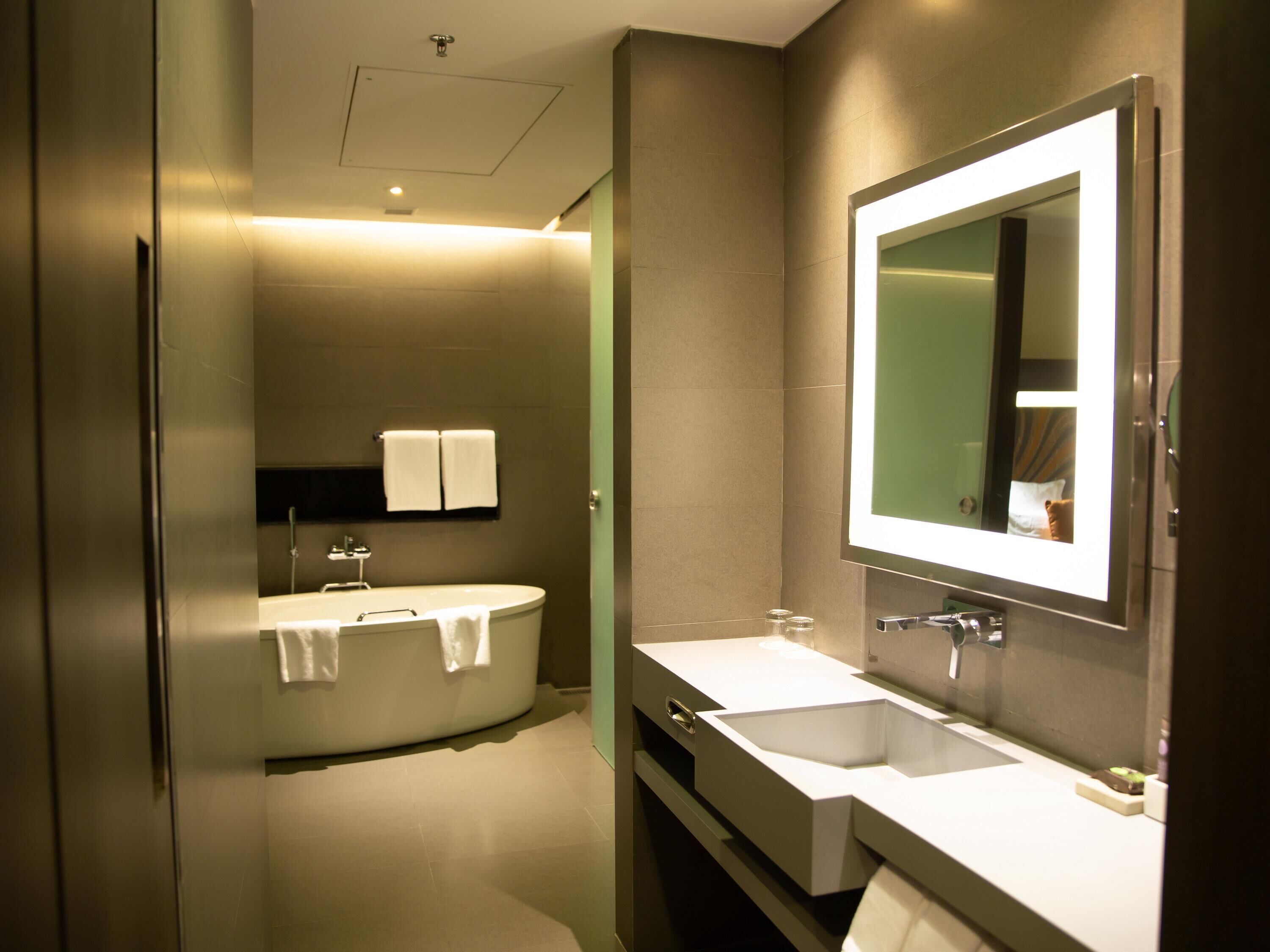 A modern bathroom with a freestanding bathtub, a large mirror, and a double sink vanity.