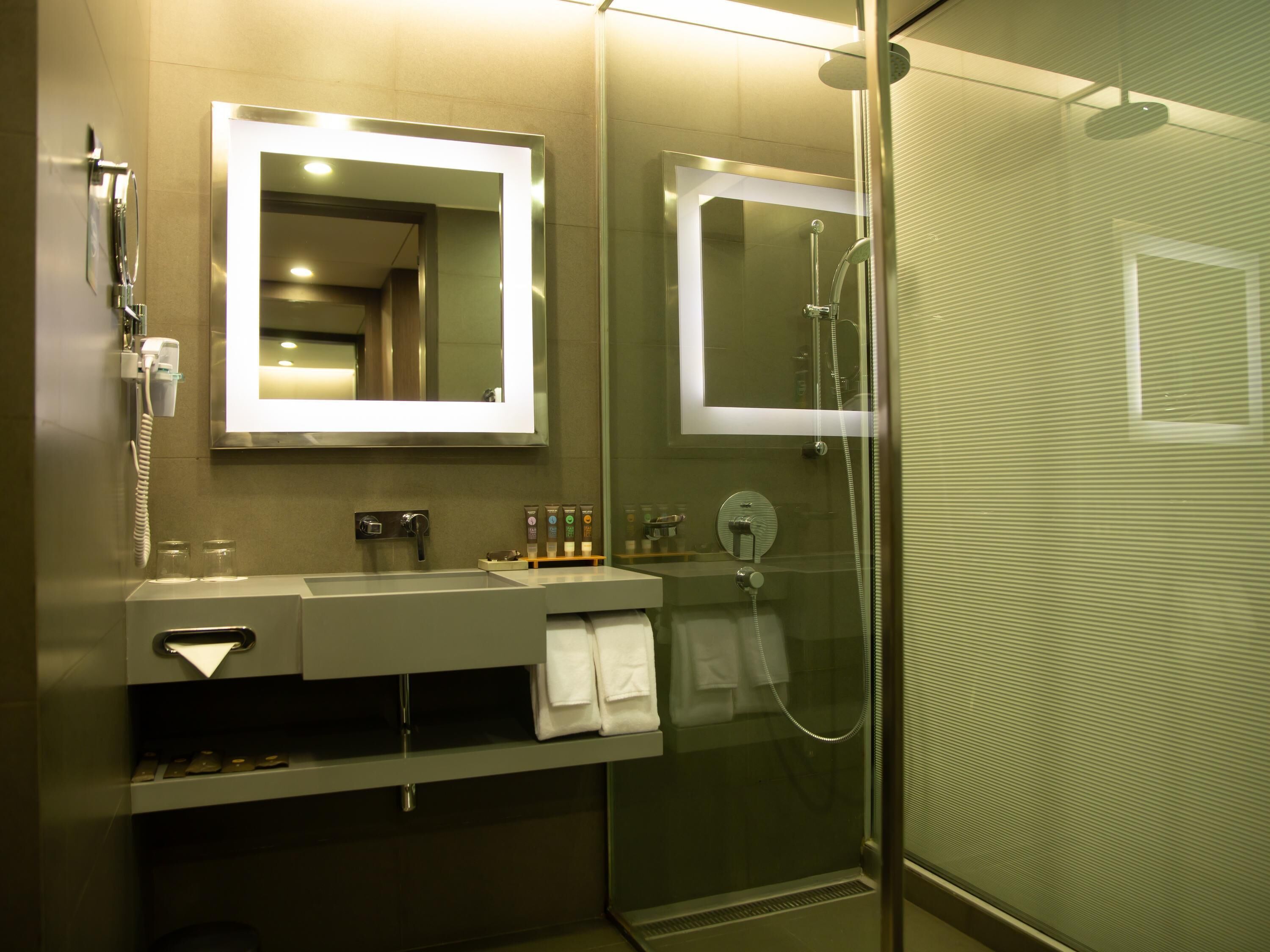 A modern bathroom with a glass-enclosed shower, a vanity with a mirror, and a telephone.