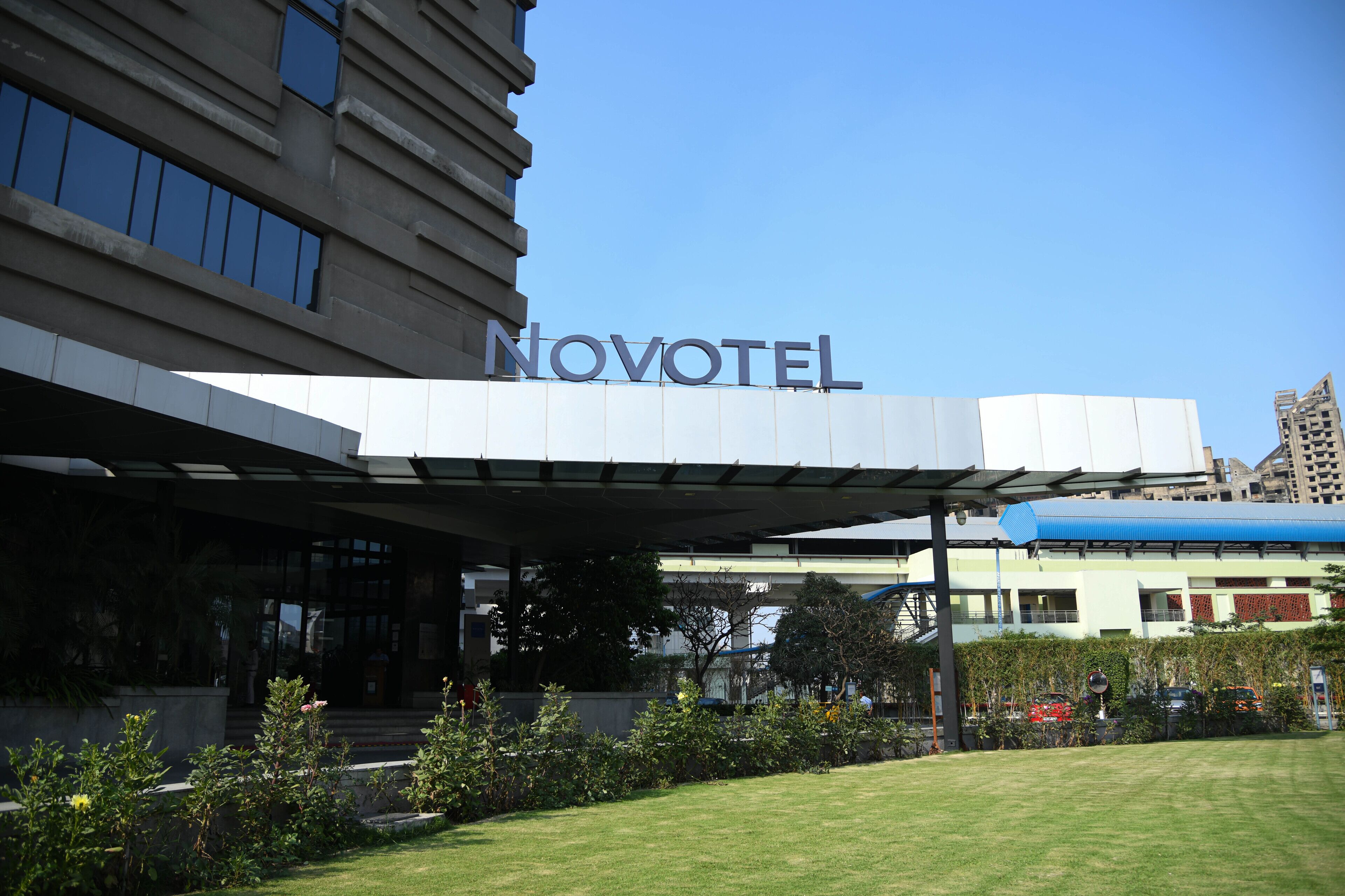 L’entrée d’un hôtel au design moderne, une allée couverte et un ciel dégagé.