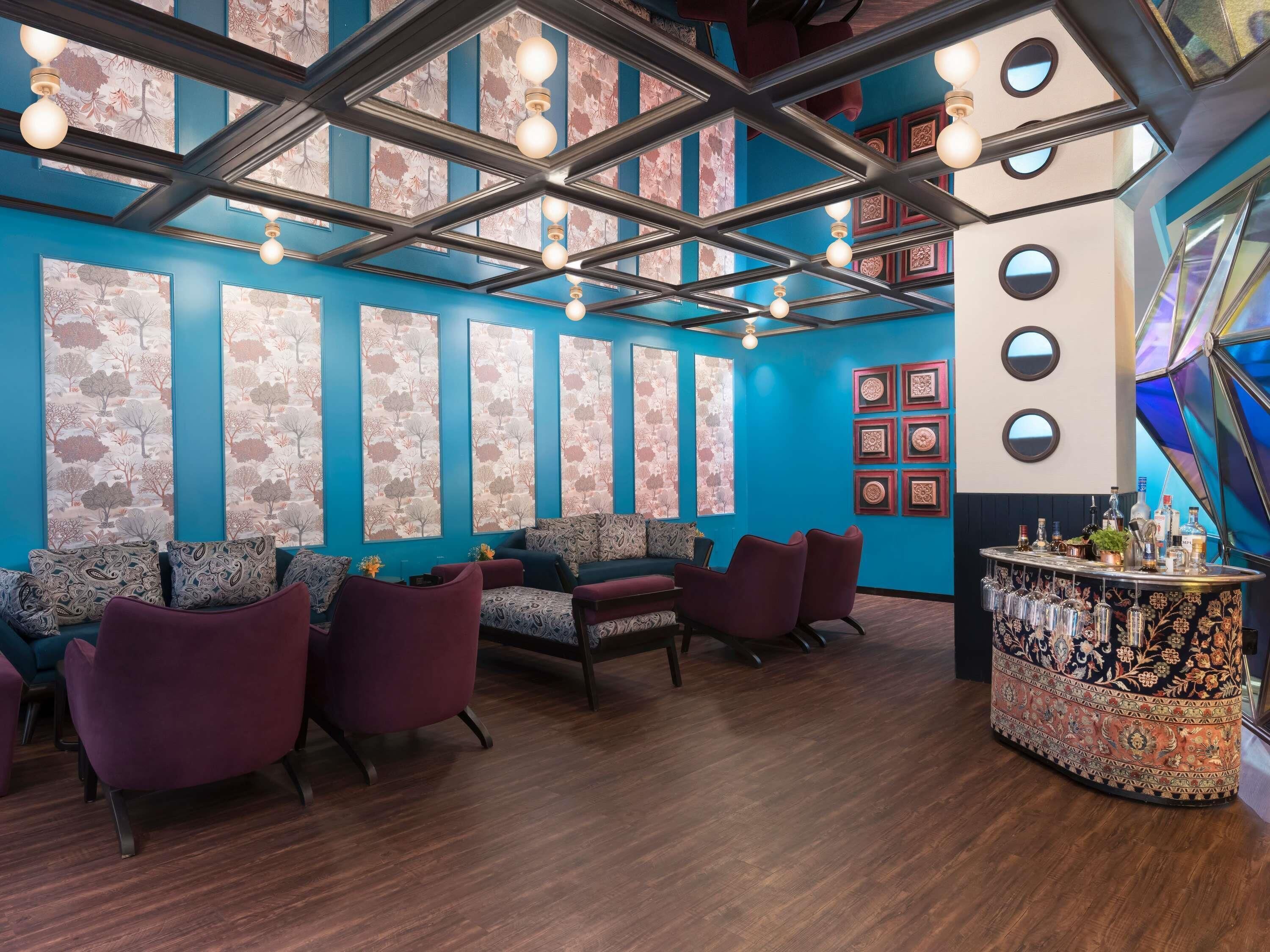 A modern interior with a blue wall, patterned wallpaper, and a bar area.