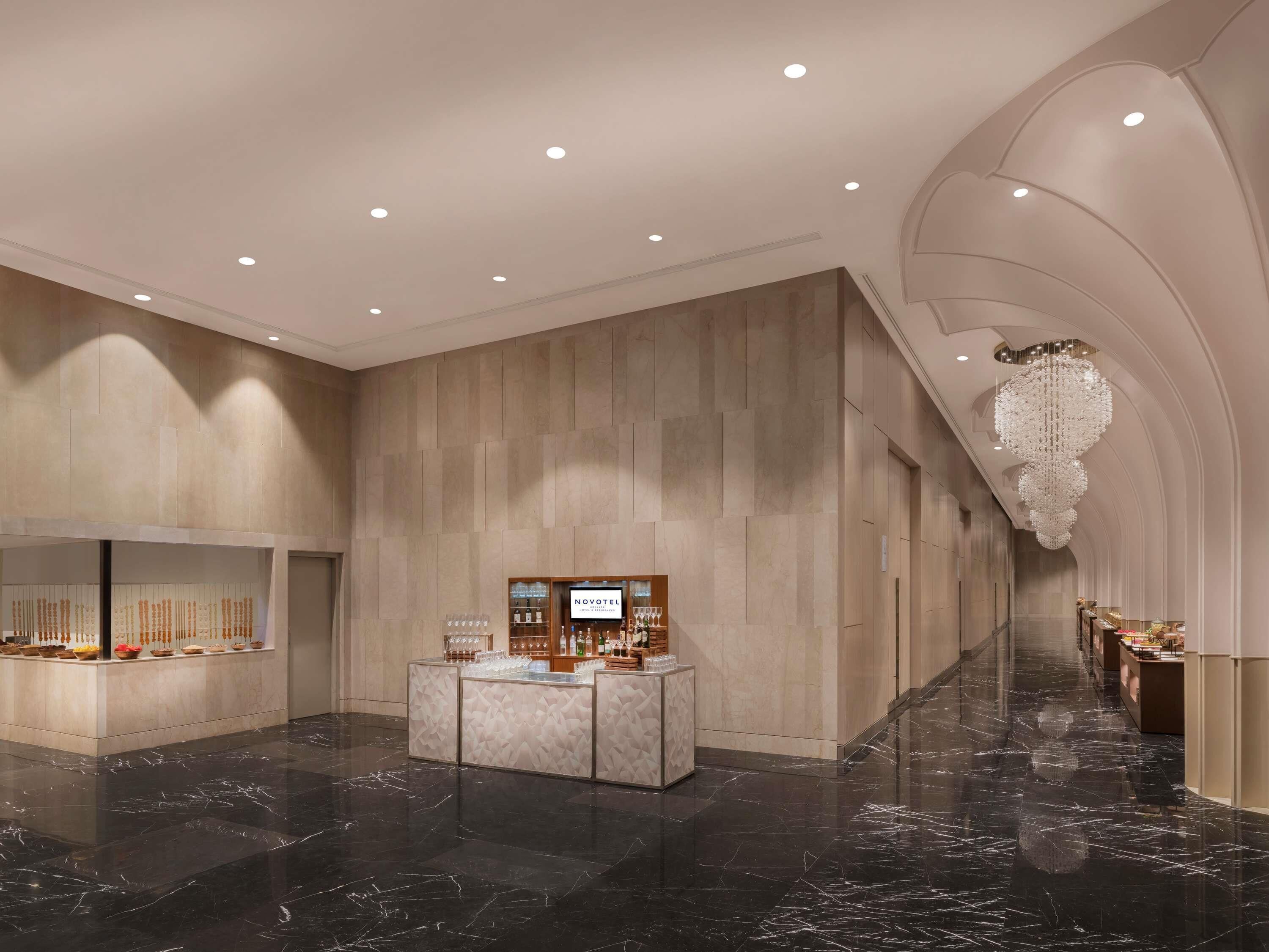 A hotel lobby with a marble floor, a reception desk, and a chandelier.