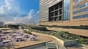 Una terraza en la azotea con mobiliario exterior y un edificio moderno al fondo.