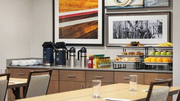 A modern kitchen with a coffee station, breakfast items, and framed artwork on the wall.