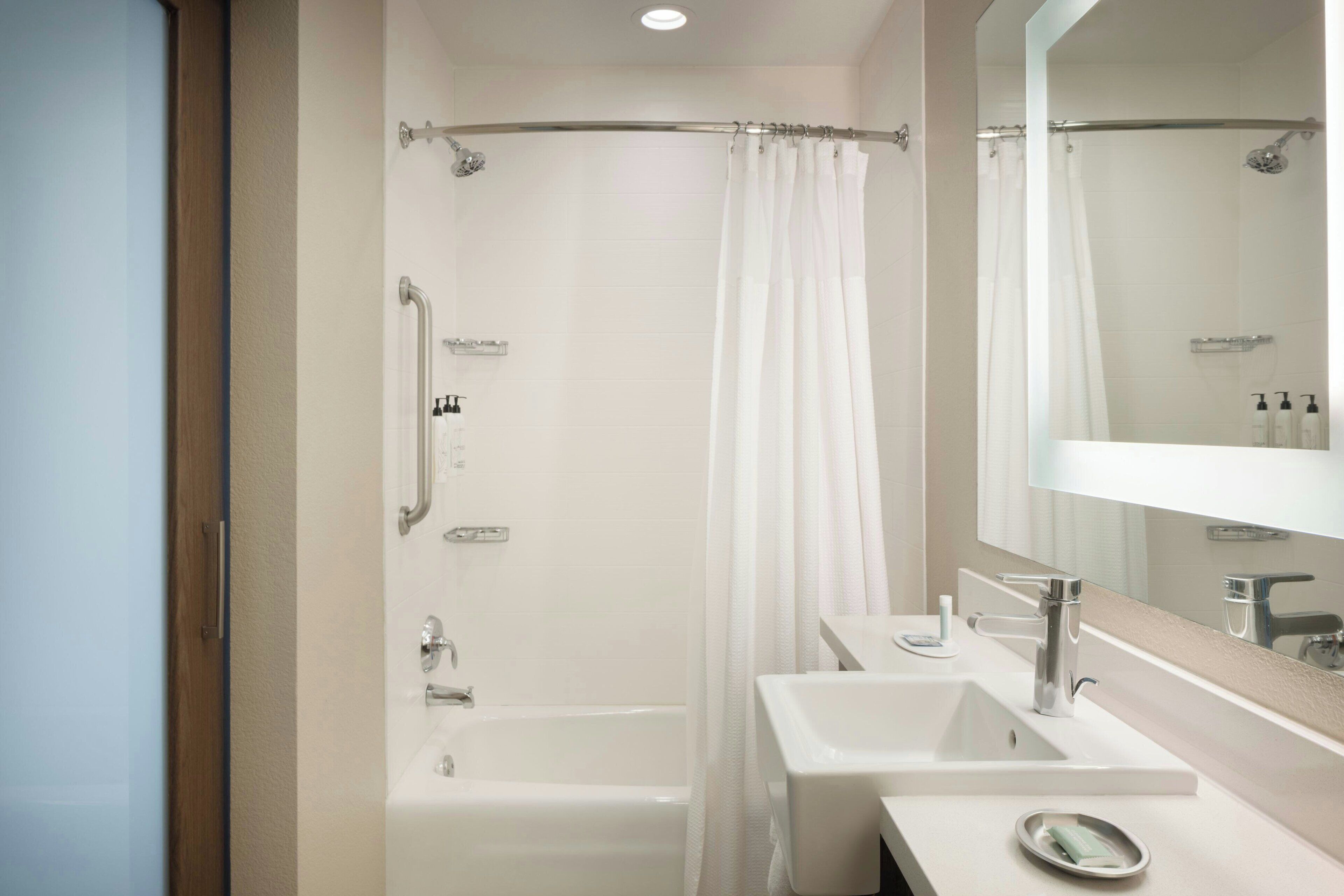 A modern bathroom with a bathtub, a shower, and two sinks.