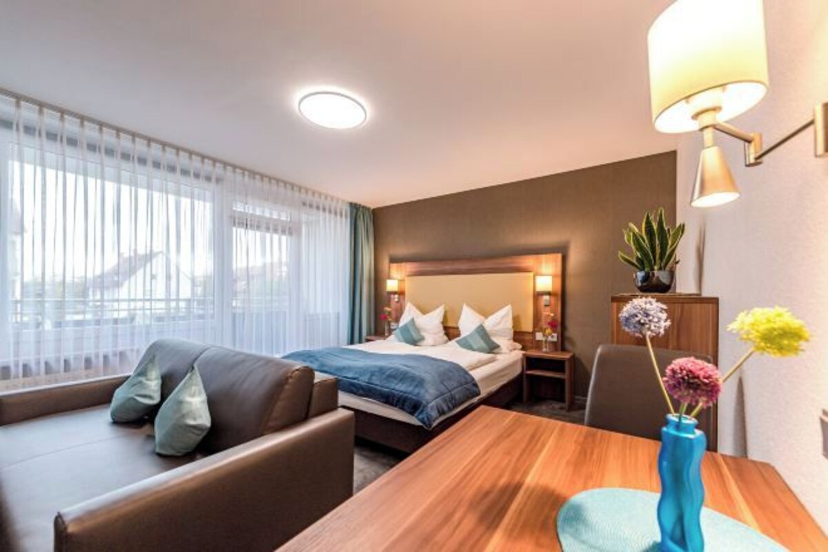 Een hotelkamer met een bed, een zithoek met een tafel en een bureau.
