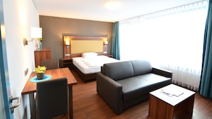 Una habitación de hotel con una cama, un sofá, un escritorio y una silla.