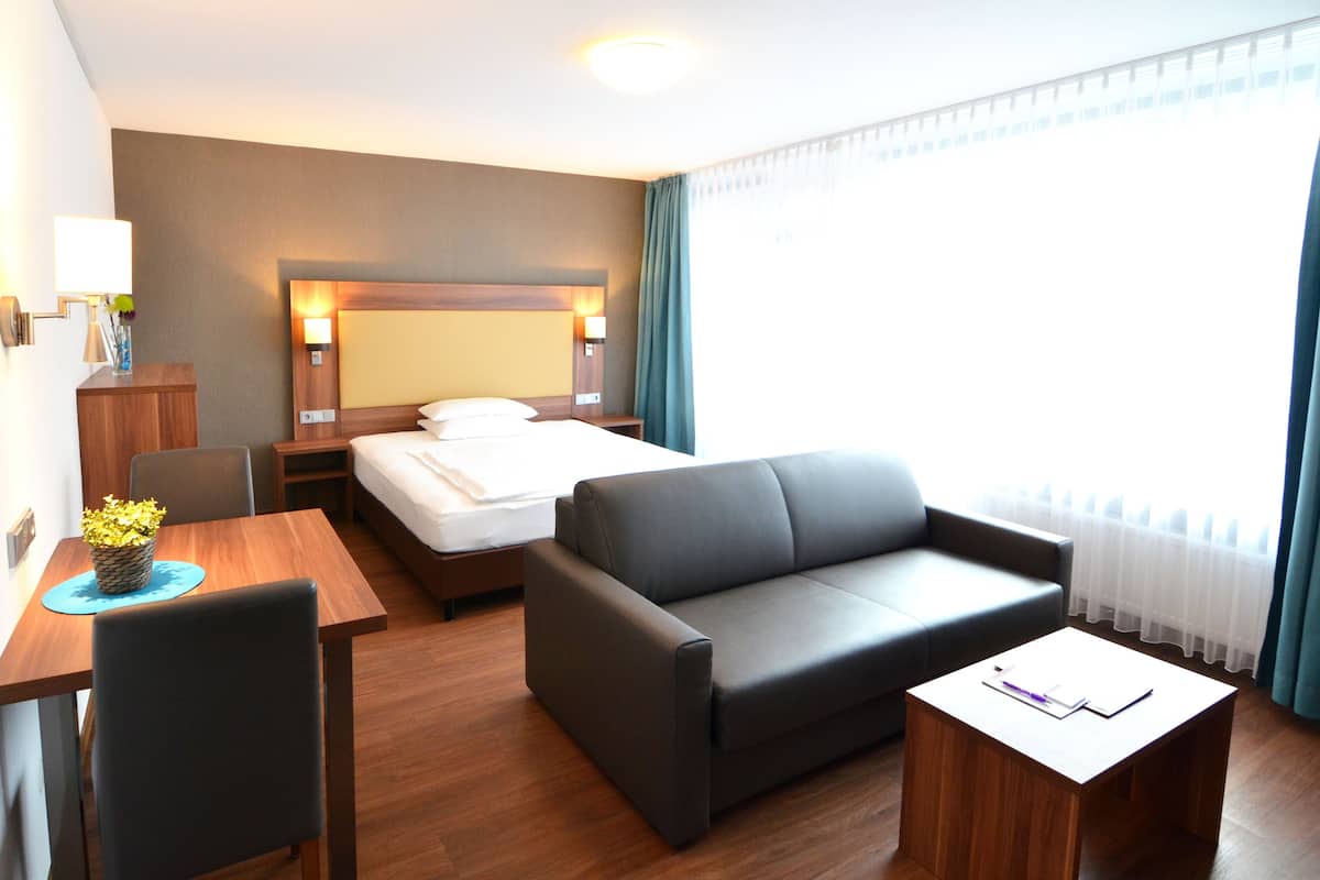 Una habitación de hotel con una cama, un sofá, un escritorio y una silla.
