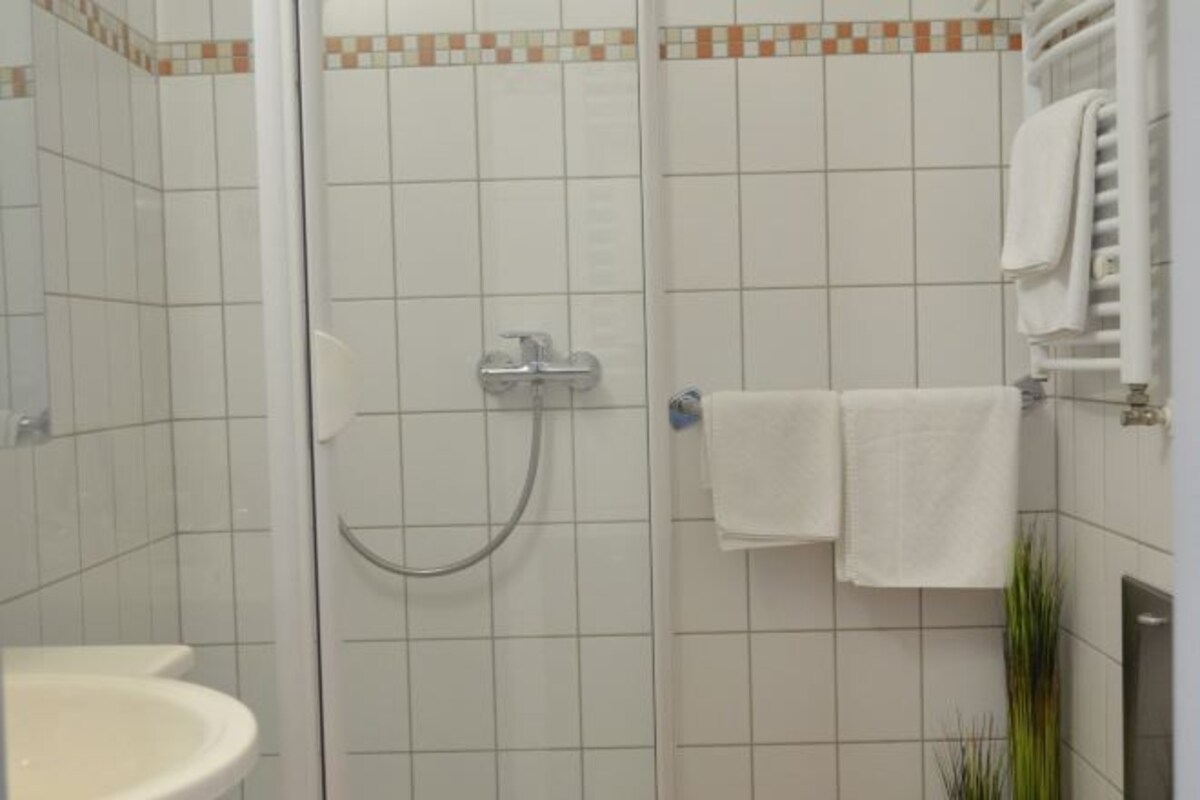 Een badkamer met een douche, wastafel en handdoekhouder.